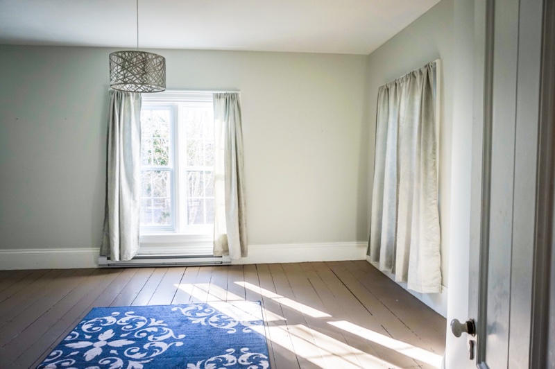grey room with 2 windows and a blue floor mat