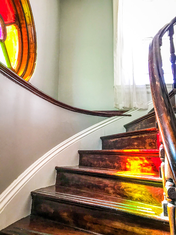 Curved staircase with round colourful window. Color is reflected on the stairs